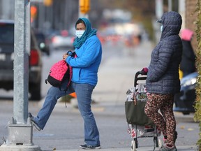 Two people wear masks while waiting for bus, on William Avenue, in Winnipeg.  Thursday, Oct. 15, 2020. Chris Procaylo/Winnipeg Sun