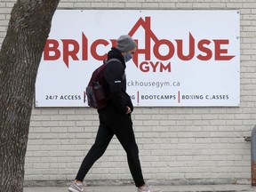 A person wearing a mask walks past the Brickhouse Gym on Friday.