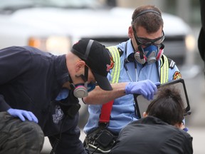 A member of the Winnipeg Fire Paramedic Service assists a person on Main Street, in Winnipeg.    Wednesday, May 13/2020.
