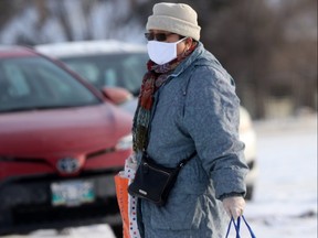 A person carries shopping across a parking lot, during the Covid-19 pandemic, in Winnipeg.  Saturday, Nov. 21, 2020.