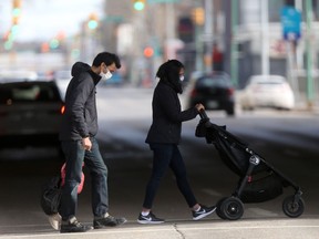People wear masks while crossing a downtown street in Winnipeg on Saturday.