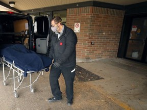 A body is loaded into a van for transport at Maples Personal Care Home on Mandalay Drive in Winnipeg on Sunday.
