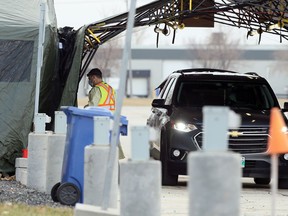 A health care employee brings a sample inside at the drive-thru COVID-19 testing site in the parking lot of Red River College.