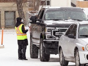 An employee conducts screening on an incoming vehicle at the COVID-19 testing site on Main Street in Winnipeg on Thurs., Nov. 12, 2020. Kevin King/Winnipeg Sun/Postmedia Network