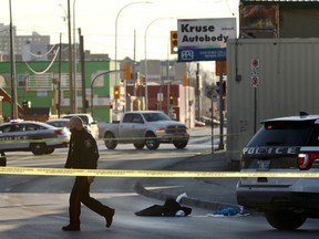 A police officer walks past a jacket along with a pile of compress bandages and a pool of blood following a shooting on Isabel Street at Elgin Avenue in Winnipeg on Mon., Nov. 16, 2020.