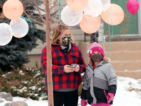 Jean Dalman and daughter Juliette, who turns eight on Tuesday, wait for the start of a car parade for her birthday outside their home on Donalda Avenue in Winnipeg on Sunday Nov. 22, 2020.