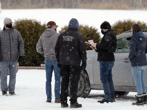 A man is given a ticket by Manitoba Justice officials for disobeying public health orders outside Church of God, south of Steinbach, Man., on Sunday, Nov. 29, 2020.