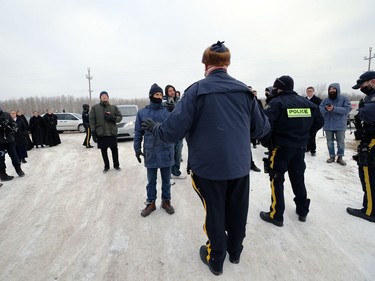 An RCMP officer in charge speaks to people outside Church of God, south of Steinbach, Man., on Sunday, Nov. 29, 2020. Officials thwarted a planned drive-by service by blocking the entrance to the church.