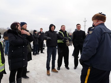 An RCMP officer in charge speaks to people outside Church of God, south of Steinbach, Man., on Sunday, Nov. 29, 2020. Officials thwarted a planned drive-by service by blocking the entrance to the church.