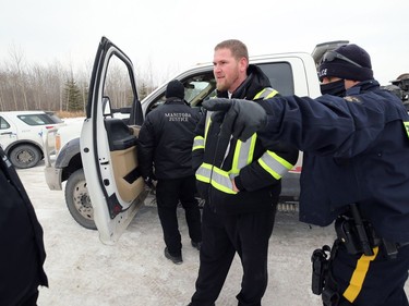 A Church of God representative is ordered away from a tow truck outside the church south of Steinbach, Man., on Sunday, Nov. 29, 2020. The man took the keys out of the ignition after RCMP had the truck ready to tow vehicles blocking the highway.