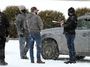 A man (second from right) is given a ticket by Manitoba Justice officials for disobeying public health orders outside Church of God, south of Steinbach, Man., on Sunday, Nov. 29, 2020.