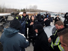 Church of God supporters pray as RCMP prepare to tow a vehicle blocking the highway outside the church south of Steinbach, Man., on Sunday, Nov. 29, 2020. RCMP blocked the entrance to the church, preventing a planned drive-in service.