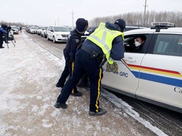 RCMP officers outside the entrance to Church of God, south of Steinbach, Man., on Sunday, Nov. 29, 2020. Supporters pulled onto the highway with the intent of entering the parking lot, blocked by RCMP, to hold a drive-by service.
