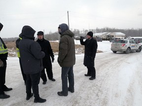 Government officials speak to Minister Tobias Tissen (centre) and other representatives of Church of God, south of Steinbach, Man., on Sunday, Nov. 29. The church was fined $5,000 and Tissen $1,296 after holding drive-in services on Sunday.