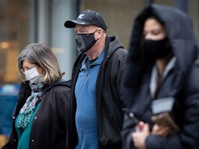 People wearing face masks to help curb the spread of COVID-19 cross a street in downtown Vancouver, B.C., Sunday, Nov. 22, 2020.