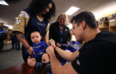 Three-month-old Kruz Cardinal is held by mother Tonya as he has his jersey signed Winnipeg Blue Bombers quarterback Zach Collaros during an autograph session in the team locker room on Tues., Jan. 28, 2020. Grandmother Laurie also came along. Kevin King/Winnipeg Sun/Postmedia Network