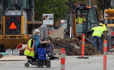 A woman in a motorized wheelchair crosses a construction area on Corydon Avenue at Guelph Street in Winnipeg on Tues., June 2, 2020. Kevin King/Winnipeg Sun/Postmedia Network