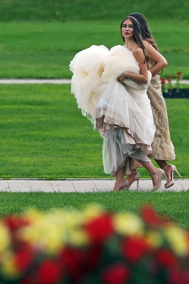 Grads carry their gowns in a light rain during a photo session on the Manitoba Legislative Building grounds in Winnipeg on Tues., June 23, 2020. Kevin King/Winnipeg Sun/Postmedia Network