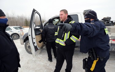 A Church of God representative is ordered away from a tow truck outside the church south of Steinbach, Man., on Sun., Nov. 29, 2020. The man took the keys out of the ignition after RCMP had the truck ready to tow vehicles blocking the highway. Kevin King/Winnipeg Sun/Postmedia Network