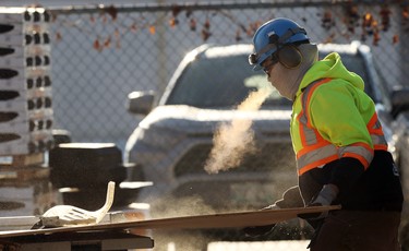 A construction worker exhales while cutting plywood at a job site off Roblin Boulevard in Winnipeg on Wed., Dec. 2, 2020. Kevin King/Winnipeg Sun/Postmedia Network