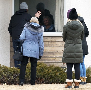 A group of people visit a resident at Charleswood Care Centre on Roblin Boulevard in Winnipeg through a window on Tues., Dec. 8, 2020. Kevin King/Winnipeg Sun/Postmedia Network