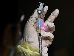 A pharmacist technician fills the Pfizer-BioNTech COVID-19 mRNA vaccine at a vaccine clinic during the COVID-19 pandemic in Toronto on Tuesday, December 15, 2020.