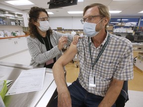 Dr. Brian Penner, with internal medicine at Winnipeg's Health Sciences Centre, receives the first COVID-19 inoculation in Manitoba from LoriAnn Laramee, a public health nurse, in the COVID-19 vaccination clinic at the Health Sciences Centre on Wednesday, Dec. 16, 2020.