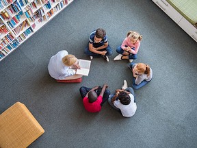 A teacher reads fairy tales to children sitting in a circle at library.