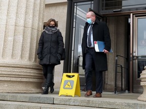 Dr. Brent Roussin (right), the chief provincial public health officer, and an assistant are mindful of a warning sign as they exit the Manitoba Legislative Building in Winnipeg after a press briefing on Tues., Dec. 8, 2020. Kevin King/Winnipeg Sun/Postmedia Network