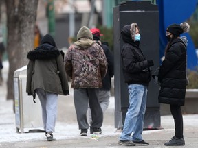 People wear masks while talking to one another, on the street in Winnipeg on Saturday.