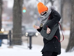 A woman wearing a mask applies hand sanitizer after stepping off a bus on Osborne Street in Winnipeg on Tuesday.