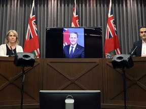 Dr. Jazz Atwal (right), Manitoba's acting deputy chief public health officer, and chief nursing officer Lanette Siragusa (right) listen as Health Minister Cameron Friesen speaks via telephone during a COVID-19 briefing at the Manitoba Legislative Building in Winnipeg on Monday, Dec. 21, 2020.