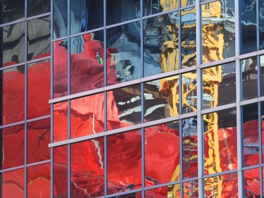 Orange tarps, a yellow crane, and human figures appear distorted, and abstract in the blue glass and straight lines of the finished building in which they are reflected, in downtown Winnipeg.  Wednesday, Feb. 19, 2020.