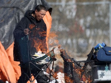 A man builds a fire at a homeless camp in Winnipeg.  The camp has reappeared after the site was cleared over the winter after a fire damaged a teepee.  There is concern that the homeless population will not be able to maintain a safe social distance to help stop the spread of Covid-19. Wednesday, March 25, 2020.