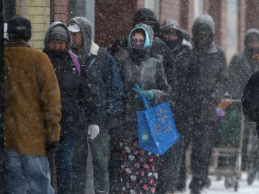 A group of people stand very close to each other while in line for food aid from Main Street Project, in Winnipeg. Thursday, April 2, 2020
