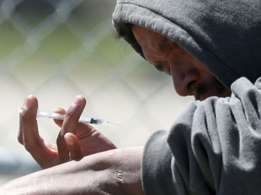 A man prepares to inject himself near the campsites that were recently ordered vacant by the City of Winnipeg. Friday, June 12, 2020.