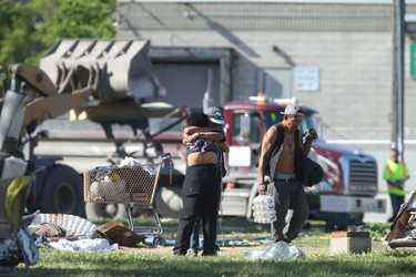 Two people embrace while a front end loader is used to remove the campsites that were recently ordered vacant by the City of Winnipeg. Friday, June 12, 2020.