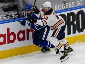 Edmonton Oilers forward Jesse Puljujarvi (13) and Toronto Maple Leafs defenseman Jake Muzzin (8) battle along the boards during the second period at Scotiabank Arena on Jan. 22, 2021.