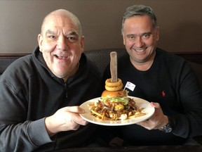 Hal Anderson poses with Pony Corral owner Peter Ginakes and the Golden Boy Poutine last year. A mixture of curds and cheese, gravy, topped with 1/2lb golden boy burger, served with bacon, cheese, mayo, lettuce, mustard, onion and chili, it is one of 149 offerings in this year's La Poutine Week which kicked off Friday.