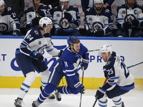 Winnipeg Jets defenceman Logan Stanley (left) checks Maple Leafs forward Zach Hyman during the first period in Toronto on Monday night. Stanley was making his NHL debut.