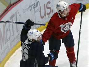 Neal Pionk (right) helps Mathieu Perreault stay upright during Winnipeg Jets training camp at Bell MTS Iceplex in Winnipeg on Sunday, Jan. 10, 2021.