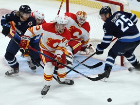 Calgary Flames centre Sean Monahan (23) grabs a loose puck from in front of goaltender Jakob Markstrom with Kyle Connor (left) and Paul Stastny pressing during NHL action in Winnipeg on Thursday, Jan. 14, 2021.