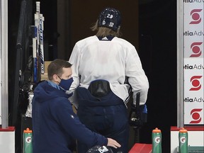 Patrik Laine leaves the ice early after grabbing his left side while speaking to head coach Paul Maurice at Winnipeg Jets practice on Sunday.