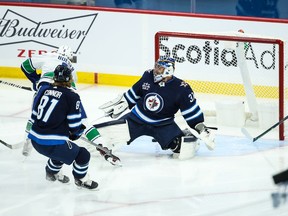 Vancouver Canucks forward Brock Boeser (6) scores on Winnipeg Jets goalie Connor Hellebuyck (37) during the first period at Bell MTS Place in Winnipeg on Saturday.
