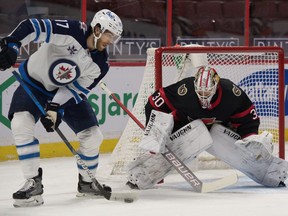 Jan 19, 2021; Ottawa, Ontario, CAN; Winnipeg Jets center Adam Lowry (17) controls the puck in front of Ottawa Senators goalie Matt Murray (30) in the first period at the Canadian Tire Centre. Mandatory Credit: Marc DesRosiers-USA TODAY Sports