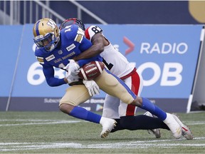 Winnipeg Blue Bombers' Marcus Sayles intercepts a pass intended for Montreal Alouettes' Eugene Lewis, who forces the fumble, during the second half of CFL action in Winnipeg, Saturday, Oct. 12, 2019.