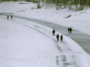 People enjoy mild weather by walking and skating along the Assiniboine River on Friday.