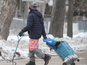 A person wears a mask while pulling a cart along a street, in Winnipeg on Tuesday, Jan. 12, 2021.