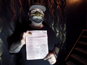 Phil McLellan, The Parlor Tattoos owner, shows the ticket he received for failing to comply with a public health emergency order, in his Winnipeg home on Monday, Jan. 11, 2021.