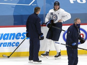Patrik Laine grabs his side and grimaces in pain while speaking to head coach Paul Maurice before an early exit at Winnipeg Jets practice on Sunday, Jan. 17, 2021.